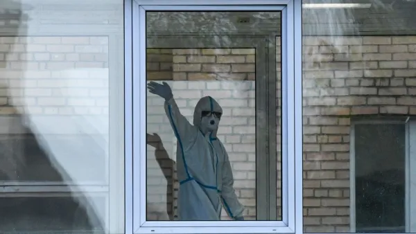 A health worker wearing protective equipment waves behind a window inside a hospital where patients infected with the COVID-19 are being treated in Khimki, outside Moscow on May 3, 2020 amid the COVID-19 outbreak, caused by the novel coronavirus. Russia on May 3, 2020 reported its largest increase in coronavirus cases with the new infections rising by more 10,000 in a single day. Kirill KUDRYAVTSEV / AFP