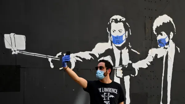 A man takes a selfie photo in front of a stencil graffiti depicting US actors John Travolta and Samuel L. Jackson in their roles of "Vincent Vega" and "Jules Winnfield" in Quentin Tarantino's "Pulp Fiction", wearing face masks, in Madrid on May 3, 2020 amid a national lockdown to prevent the spread of the COVID-19 disease. Spain today counted another 164 coronavirus deaths, the lowest daily number in nearly seven weeks as the country begins to gradually lift its strict lockdown. The figures from the health 