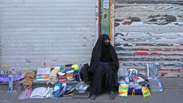 An Iranian street vendor wearing a protective mask amid the novel coronavirus pandemic, sits by her display of goods on a street of the capital Tehran, on May 09, 2020. ATTA KENARE / AFP