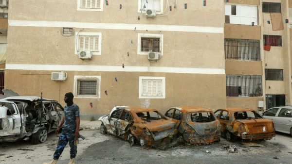 A fighter loyal to Libya's UN-recognised Government of National Accord (GNA) stands next to destroyed cars following bombardment earlier in the day in the residential Bab Bin Ghashir neighbourhood of Libya's capital Tripoli, on May 9, 2020. (AFP/File)