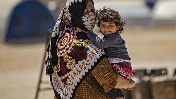 A displaced Syrian woman walks with her child at the Washukanni camp for the internally displaced in Syria's northeastern Hasakeh province on May 10, 2020, during the Muslim holy month of Ramadan. DELIL SOULEIMAN / AFP