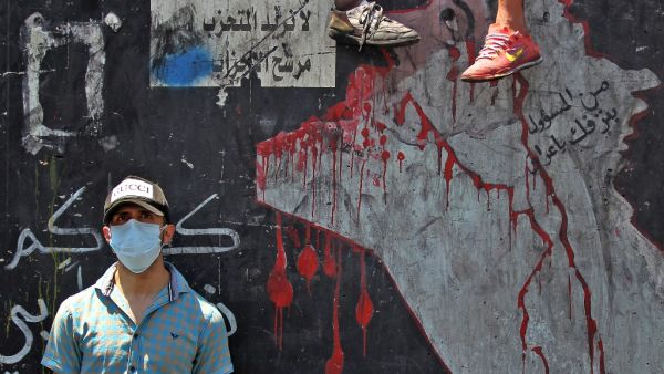 An Iraqi protester, wearing a protective mask, is pictured on the Al-Jumhuriyah bridge in the capital Baghdad on May 11, 2020, during an anti-government demonstration. Modest anti-government rallies resumed in some Iraqi cities Sunday, clashing with security forces and ending months of relative calm just days after Prime Minister Mustafa Kadhemi's government came to power. The protests first erupted in Baghdad and Shiite-majority southern cities in October, demanding an end to corruption and unemployment an