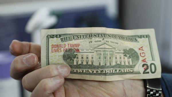 A customer pays with a $20 bill that has been stamped "Donald Trump Lives Here" after having his hair cut by barber Karl Manke, who faces two misdemeanor charges for reopening his business despite state shutdown orders, on May 12, 2020 in Owosso, Michigan. (AFP)