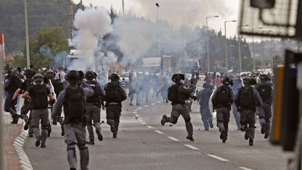 Tear gas fumes are seen as Israeli security forces run during clashes with protesters in a demonstration near the northern Arab Israeli city of Arara on May 14, 2020, after a man was shot to death after stabbing a security guard outside Tel Hashomer Hospital. Ahmad GHARABLI / AFP