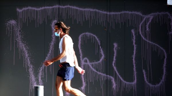 A man clad in mask due to the COVID-19 coronavirus pandemic walks past a graffiti reading "VIRUS" on the facade of a fortified local branch of the Bank of Beirut in the Lebanese capital on May 18, 2020. Lebanon is ready to terminate a 23-year-old dollar peg and float the pound, but only after it secures billions in aid, Finance Minister Ghazi Wazni had said on May 15. After talks started with the International Monetary Fund (IMF) on a plan to rescue Lebanon's crisis hit economy, he also said banking sector 