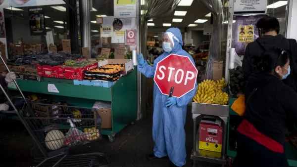 A worker wearing a full body suit holds a STOP sign in front of a Food market as he manages the flow of the customers on May 18, 2020 in the Jackson Heights neighbourhood of Queens in New York City. Johannes EISELE / AFP