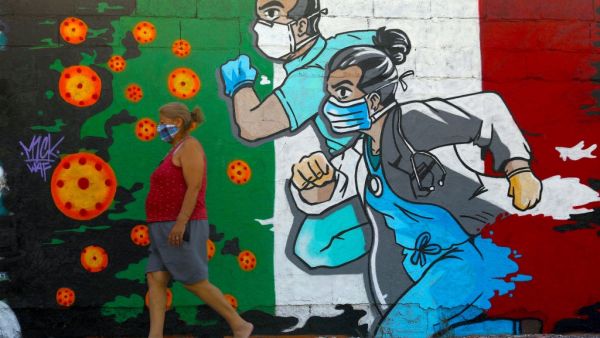 A woman walks past a coronavirus-related mural painted by artist Mick Martinez in Ciudad Juarez, state of Chihuahua, Mexico, on May 19, 2020. HERIKA MARTINEZ / AFP