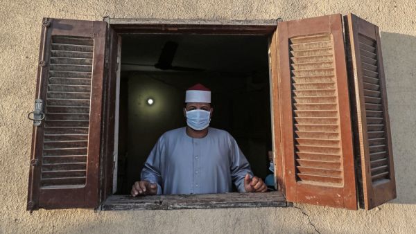 The Imam of a local mosque in the village of Shamma in Egypt's northern Nile delta province of Menoufia stands clad in mask due to the COVID-19 coronavirus pandemic by a window near the mosque early on May 24, 2020, before the prayers of Eid al-Fitr, the Muslim holiday which starts at the conclusion of the holy fasting month of Ramadan. (AFP/File Photo)