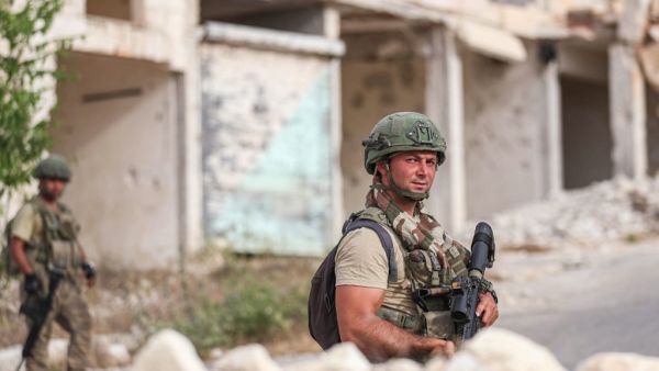 Turkish soldiers patrol along a road past destroyed buildings atop the Arbaeen hill overlooking Ariha in the southern countryside of Syria's Idlib province on May 26, 2020. OMAR HAJ KADOUR / AFP