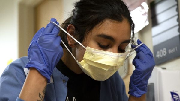 Charge nurse Liliana Palacios carefully removes her mask and PPE after tending to a patient with COVID-19 in the acute care COVID unit at Harborview Medical Center on May 7, 2020 in Seattle, Washington. (AFP)