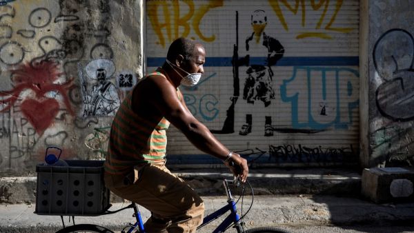 A man wears a face mask as he rides a bicycle in Havana, on May 25, 2020. Cuba reported 1947 confirmed cases of COVID-19 and 82 deceased due to the virus. YAMIL LAGE / AFP