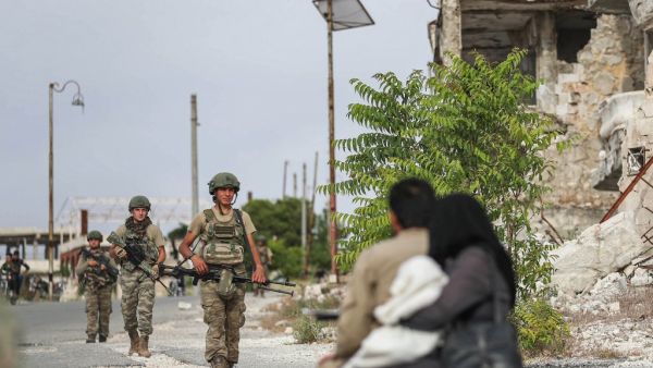 Turkish soldiers patrol along a road past destroyed buildings atop the Arbaeen hill overlooking Ariha in the southern countryside of Syria's Idlib province on May 26, 2020. OMAR HAJ KADOUR / AFP