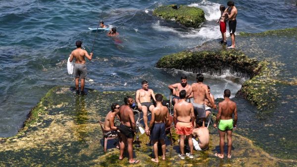 Residents of the Lebanese capital Beirut gather on the rocks along the seaside corniche, despite the lingering threat of the novel coronavirus, on May 31, 2020. ANWAR AMRO / AFP