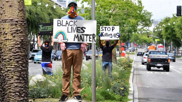 Activists hold placards in the middle of Santa Monica Boulevard in West Hollywood, California over the death of George Floyd, on June 1, 2020. The city and county of Los Angeles has extended curfew for a third night following a weekend of looting in southern California by people taking advantage of those protesting the death of George Floyd. Frederic J. BROWN / AFP