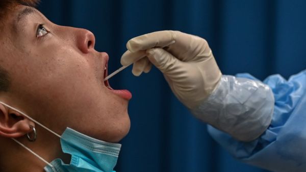This file photo taken on May 14, 2020 shows a medical worker taking a swab sample from a man to be tested for the COVID-19 coronavirus in Wuhan in China’s central Hubei province. Chinese authorities have completed a mass coronavirus testing campaign in Wuhan, finding only 300 positive results among nearly 10 million people in the city where the pandemic began, local officials said on June 2, 2020. Hector RETAMAL / AFP