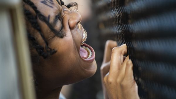 A woman shouts at a line of policemen standing near a metal fence recently erected in front of Lafayette Square near the White House to keep protestors at bay on June 2, 2020. Protesters returned to the area after they were tear gassed on June 1, 2020, to open the way for US President Donald Trump to walk to the church for a photo-op.  ROBERTO SCHMIDT / AFP