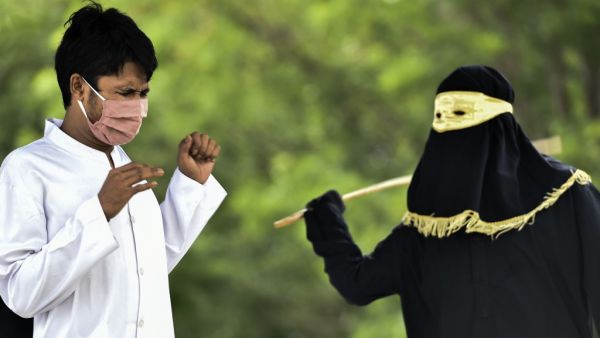 A man reacts as he receives 100 whippings by religious police as punishment for pre-marital sex, outside a mosque in Jantho, Aceh province on June 5, 2020. CHAIDEER MAHYUDDIN / AFP