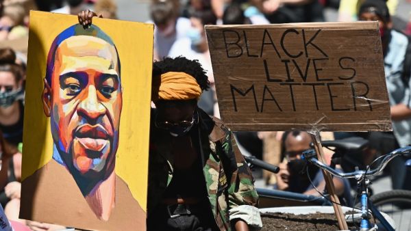 Protesters hold up signs during a "Black Lives Matter" protest in front of Borough Hall on June 8, 2020 in New York City. On May 25, 2020, Floyd, a 46-year-old black man suspected of passing a counterfeit $20 bill, died in Minneapolis after Derek Chauvin, a white police officer, pressed his knee to Floyd's neck for almost nine minutes.  Angela Weiss / AFP
