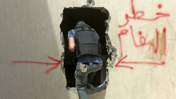 A Turkish deminer enters a house through a hole in the wall with a warning about the presence of mines in the Salah al-Din area, south of the Libyan capital Tripoli, on June 15, 2020. Human Rights Watch earlier this month accused pro-Haftar forces of laying Russian and Soviet-era landmines as they withdrew from Tripoli's southern districts. A team of Turkish deminers arrived in Tripoli last week to bring their expertise, under a broader military cooperation agreement signed late last year between Tripoli an