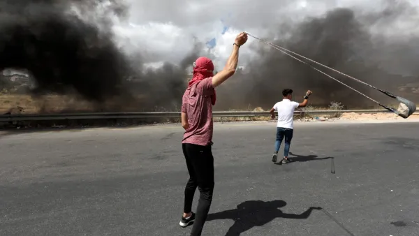 A Palestinian demonstrator uses a slingshot to hurl rocks at Israeli troops during a protest against Israel's plan to annex parts of the occupied West Bank, near the city of Ramallah, on June 19, 2020. Israel intends to annex West Bank settlements and the Jordan Valley, as proposed by US President Donald Trump, with initial steps slated to begin from July 1. ABBAS MOMANI / AFP