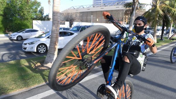 Saudi youths ride bicycles at the seafront promenade in the Saudi seaport of jeddah, on June 21, 2020, as the country re-opens following the lifting of a lockdown due to the COVID-19 pandemic. AMER HILABI / AFP
