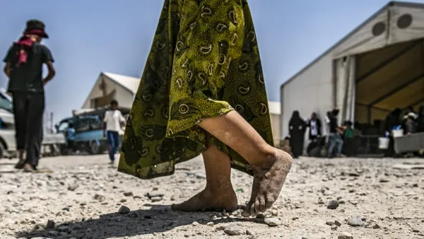 In this file photograph taken on July 22, 2019, a young child walks barefoot at al-Hol camp for displaced people, in al-Hasakeh governorate, north-eastern Syria, as people collect UN-provided humanitarian aid packages. The government said June 22, 2020, that it had brought home 10 French children of jihadist fighters overnight from a refugee camp in Syria, the latest in a piecemeal repatriation process since the Islamic State group was ousted from its Syrian base in March 2019. Delil souleiman / AFP