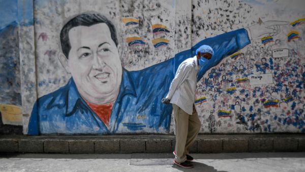 A man wearing a protective mask walks past a mural depicting Venezuela's late president (1999-2013) Hugo Chavez at the Perez de Leon Hospital of the Petare neighbourhood, in eastern Caracas on June 23, 2020, amid the new coronavirus pandemic. In Petare, the largest slum in Venezuela, more than 100 professionals of Doctors Without Borders face the COVID-19 pandemic getting around the crisis in the country's public healthcare sector. Federico PARRA / AFP