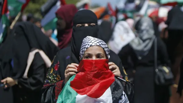A Palestinian woman fastens a national flag as a mask on the face of a girl during a demonstration against Israel's West Bank annexation plans in Gaza City on July 1, 2020. Expectations of a major Israeli announcement on controversial annexations in the occupied West Bank dimmed, as global criticism of the project mounted and Palestinian protesters began gathering in Gaza. Mohammed ABED / AFP