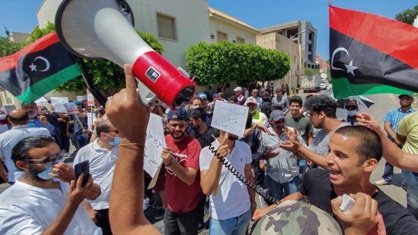 Libyans lift placards at a rally in front of the Prime Ministers headquarters in the capital Tripoli to protest frequent electricity cuts, on July 1, 2020. Mahmud TURKIA / AFP