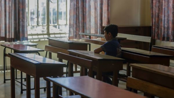 A Lebanese pupil looks out of the window as he sits in his empty classroom after coming to collect the books he left before the COVID-19 lockdown, at Our Lady of Lourdes school in the Lebanese city of Zahle, in the central Bekaa region, on June 30, 2020. (AFP)