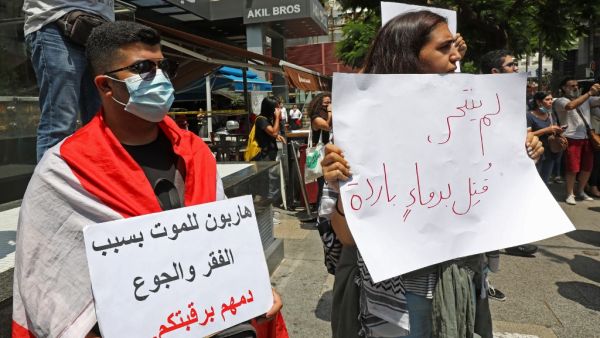 A demonstrator carries a placard (R) which reads in Arabic " He did not commit suicide, he was killed in cold blood" as they gather to denounce the death of a 61-year-old man, who committed suicide due to the country's deepening economic downturn, in the capital Beirut's Hamra street on July 3, 2020. ANWAR AMRO / AFP