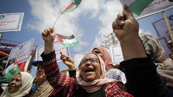 Palestinian women lift national flags and placards during a rally for supporters of the Fateh movement against Israel's West Bank annexation plans, in Beit Hanun in the north of the Gaza Strip, on July 6, 2020. MOHAMMED ABED / AFP