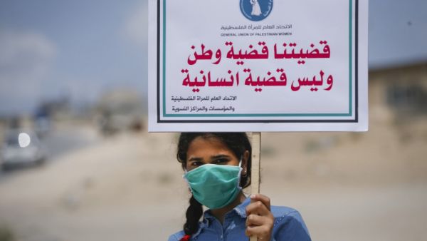 A Palestinian girl wearing a protective mask amid the COVID-19 pandemic lifts a placard which reads "Our cause that of a homeland, not a humanitarian one", during a rally for supporters of the Fateh movement against Israel's West Bank annexation plans, in Beit Hanun in the north of the Gaza Strip, on July 6, 2020. Mohammed ABED / AFP
