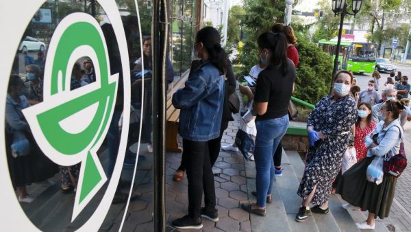 In this file photo taken on June 29, 2020 People wearing face masks stand in a line outside a pharmacy in Almaty. Ruslan PRYANIKOV / AFP