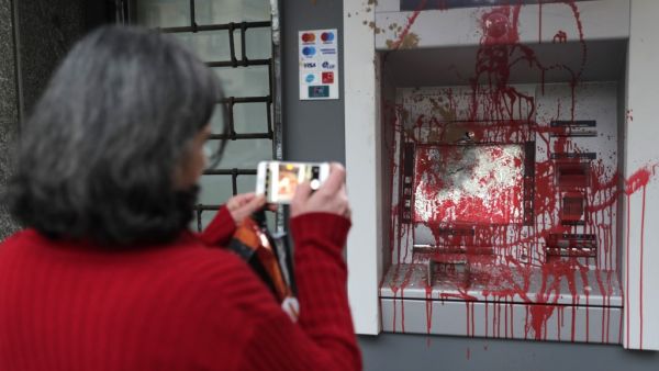 In this file photo taken on January 15, 2020 A woman pictures an ATM machine that was vandalised the previous night by anti-government protesters in the Lebanese capital Beirut. For months, Lebanon has grappled with its worst economic crisis since the 1975-1990 civil war. Tens of thousands have lost their jobs or part of their salaries, while a crippling dollar shortage has sparked rapid inflation.  ANWAR AMRO / AFP