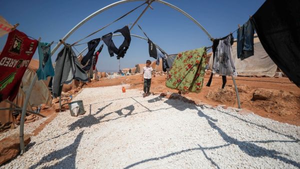 A displaced Syrian boy stands next to clothes at a camp for displaced Syrians from Idlib and Aleppo provinces, near the town of Maaret Misrin in Syria's northwestern Idlib province on July 11, 2020. The Idlib region, Syria's last major opposition bastion, is home to some three million people, nearly half of whom have been displaced from other regions. OMAR HAJ KADOUR / AFP