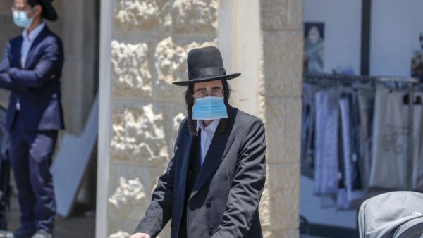 An Ultra-Orthodox Jewish man, wearing a protective face mask, stands at a checkpoint erected to block entrance to the neighbourhoods of Romema and Kiryat Belz after authorities imposed a lockdown to combat the spread of the Coronavirus, in Jerusalem on July 12, 2020. AHMAD GHARABLI / AFP
