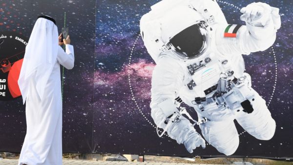 In this file photo taken on September 25, 2019 a man takes a picture of an illustration depicting an astronaut with the Emirati national flag outside Mohammed Bin Rashid Space Centre (MBRSC) in Dubai, ahead of the launching of Soyuz MS-15 spacecraft from Baikonur Cosmodrome in Kazakhstan. Hazzaa al-Mansoori, 35, who will spend eight days on the ISS, will make history by becoming the first Arab on the International Space Station but not the first Muslim. KARIM SAHIB / AFP