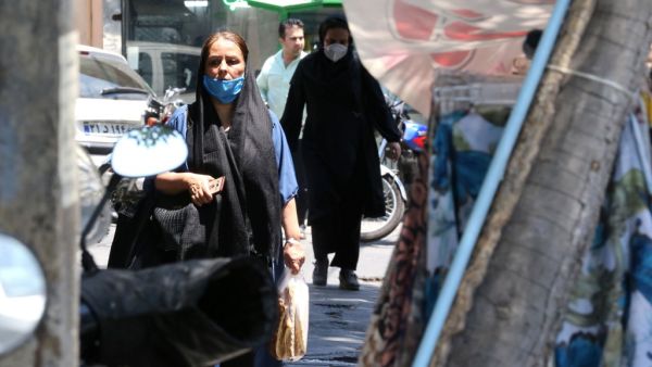 Mask-clad Iranians walk along a street in the capital Tehran, amid the ongoing novel coronavirus pandemic crisis, on July 19, 2020. Iran's president said yesterday that 35 million Iranians may contract the coronavirus, as the country still did not have herd immunity although a quarter of the population may have already been infected. The country has been battling a resurgence of COVID-19, with figures showing a rise in both new infections and deaths since a two-month low in May. ATTA KENARE / AFP