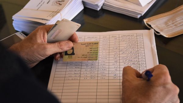 A voting official registers a woman to vote at a polling station in the Nubl neighbourhood of Aleppo on July 19, 2020, during the parliamentary elections. Syrians vote today to elect a new parliament as the Damascus government grapples with international sanctions and a crumbling economy after retaking large parts of the war-torn country. AFP 