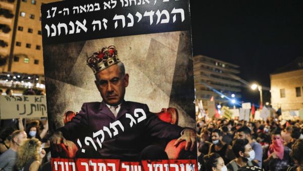 A poster is raised showing Israeli Prime Minister Benjamin Netanyahu wearing a crown and a line across his chest reading in Hebrew "expired" above another line reading "the madness of King Bibi", and other text (top) reading "Bibi we are not in the 17th century, we are the state" during a demonstration against the Israeli government near the Prime Minister's residence in Jerusalem on July 25, 2020. Ahmad GHARABLI / AFP