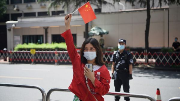 A woman waves a Chinese flag in front of the US consulate in Chengdu, southwestern China's Sichuan province on July 26, 2020. Tensions have soared between the two powers on a range of fronts including trade, China's handling of the novel coronavirus and a tough new security law for Hong Kong, with US officials this week warning of a "new tyranny" from China. Noel Celis / AFP
