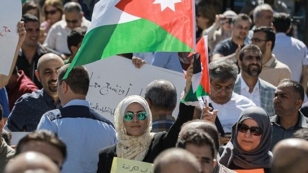 A woman raises a Jordanian national flag as she stands amidst public school teachers demonstrating and demanding pay raises, at the Professional Associations Complex in Jordan's capital Amman on October 3, 2019. (File/AFP)