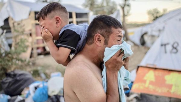Man and boy cry after police fire tear gas during clashes at Moira refugee camp on the Greek island of Lesbos on Sunday (AFP)