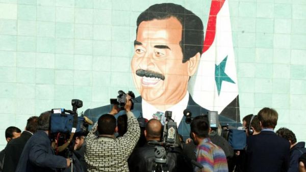 Foreign and local cameramen crowd in front of a mural of late Iraqi President Saddam Hussein in 2002. (AFP)