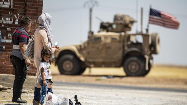 A family stands across a US military vehicle parked on the outskirts of Rumaylan (Rmeilan) in Syria's Kurdish-controlled northeastern Hasakeh province, on July 16, 2020. Delil SOULEIMAN / AFP
