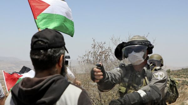 An Israeli border guard sprays pepper spray towards a Palestinian demonstrator during a protest against Jewish settlements and Israel's planned annexation of parts of the Israeli-occupied West Bank, in the town of Asira Shamaliya near the West Bank city of Nablus on July 17, 2020. JAAFAR ASHTIYEH / AFP