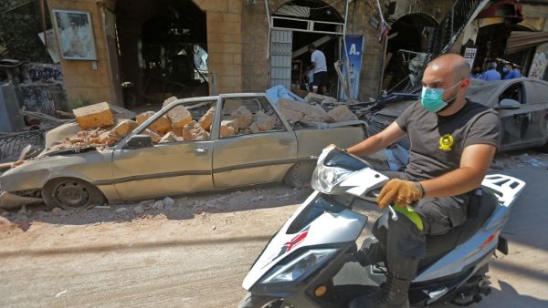 A man wearing a protective mask against the coronavirus rides his motorbike past damaged cars and shops in Beirut's commercial Gemmayzeh district, one day after a powerful twin explosion tore through Lebanon's capital, resulting from the ignition of a huge depot of ammonium nitrate at the city's main port. Rescuers searched for survivors in Beirut after a cataclysmic explosion at the port sowed devastation across entire neighbourhoods, killing more than 100 people, wounding thousands and plunging Lebanon de