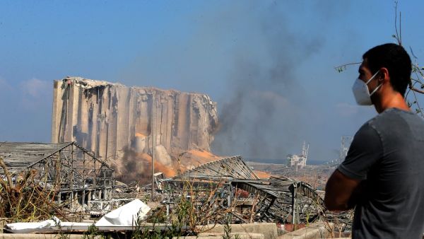 A man wearing a protective mask against the coronavirus stands across the road from the damaged grain silos of Beirut's harbour August 5, 2020, one day after a powerful twin explosion tore through Lebanon's capital, resulting from the ignition of a huge depot of ammonium nitrate at the city's main port. Rescuers searched for survivors in Beirut after a cataclysmic explosion at the port sowed devastation across entire neighbourhoods, killing more than 100 people, wounding thousands and plunging Lebanon deepe