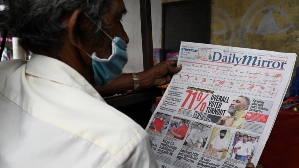 A man reads a newspaper with a headline on Sri Lanka's parliamentary polls 71% turnout, in Colombo on August 6, 2020.  LAKRUWAN WANNIARACHCHI / AFP